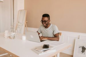 smiling man typing on a laptop